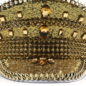 Detail of gold captain hat with shimmering sequins, metallic studs and amber gemstones