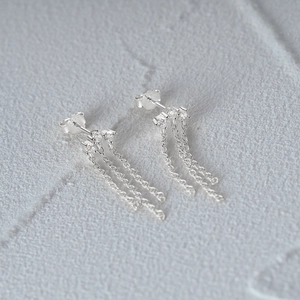 Detailed macro view of S925 sterling silver stamp on shimmering triple chain tassel earrings