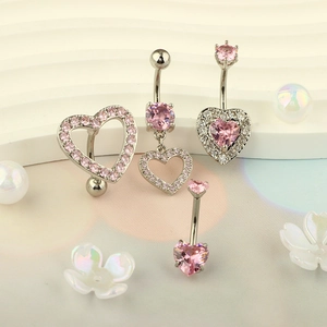 Macro detail of silver heart belly rings with pink zircon stones on decorative background