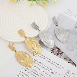 Detail of gold and silver lava texture oval drop earrings on minimalist display