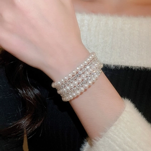 Detail of layered pearl bracelet with rhinestones worn on a model against a fuzzy sweater