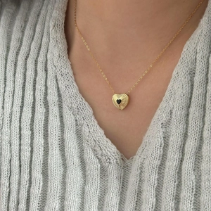 Macro view of gold heart necklace with black inlay on a soft knitted sweater
