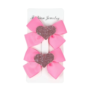 Set of two pink grosgrain hair bows with purple glitter hearts on a display card