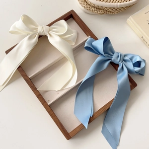 Detail of large cream and sky blue satin bow hair clips on a rustic wooden tray