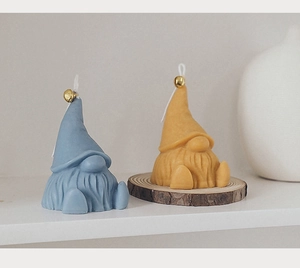 Detail of gnome-shaped scented candles in grey and yellow with small gold bells