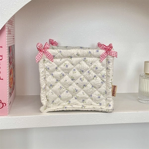 Detail of quilted floral storage basket with pink checkered bows and brand label