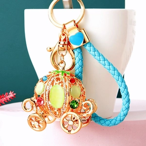 Detailed close-up of a crystal pumpkin carriage keychain with blue woven leather strap