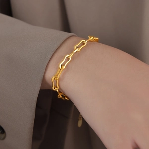 Elegantes goldenes Gliederkettenarmband mit Wellenmuster getragen zum Blazer Ärmel