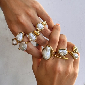 Macro shot of layered baroque pearl rings in gold finish on female hand