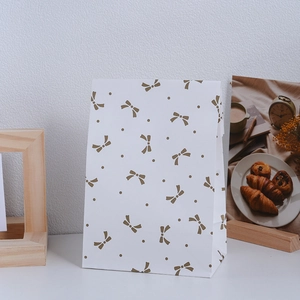 Elegant white paper gift bag with golden bow pattern and dots for treats and jewelry