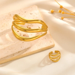 Vue détaillée d'un ensemble bracelet et bague doré mat avec motif à vagues sur pierre