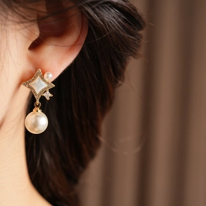 Vue macro d'une boucle d'oreille dorée avec perle, nacre et détails en zircone