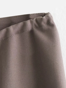 Detailed close-up of double-stitched waist seams on dark taupe minimalist trousers