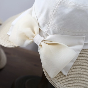 Close-up of the large organza bow and straw weave texture on a white sun hat for women