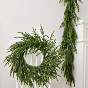 Artificial evergreen Christmas wreath and garland set displayed on a white chair