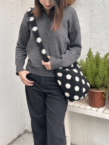 Détail d'un sac seau en peluche à pois noirs et blancs avec texture douce sur mannequin