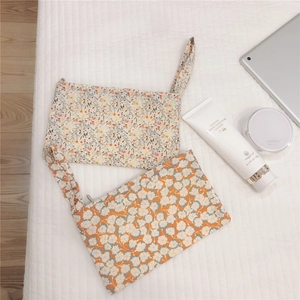 Floral cotton wristlet bags for cosmetics and phone storage on white quilted surface