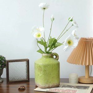 Vintage grüne Keramikvase mit weißen Mohnblumen in gemütlicher Wohndekoration