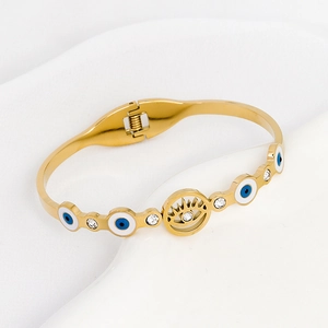 Gold evil eye bangle with blue enamel and sparkling zircons on white surface