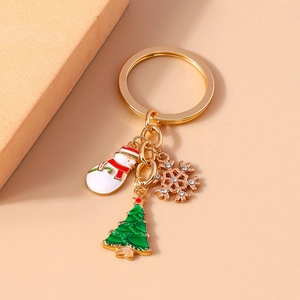 Close-up of Christmas snowman and tree enamel pendants on a golden metal keychain