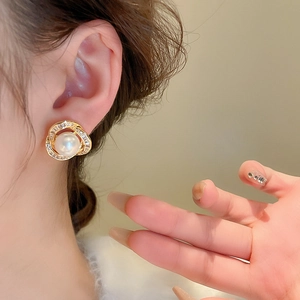 Détail d'une boucle d'oreille perle avec monture spirale dorée et micro-pavé de oxydes