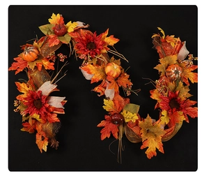 Dettaglio ghirlanda autunnale con foglie di acero, zucche, girasoli e nastro dorato