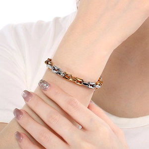 Detalle de la pulsera de cadena bicolor oro y plata llevada en la muñeca con estilo moderno