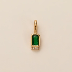 Detail view of gold pendant with emerald rectangle stone and four small white diamonds