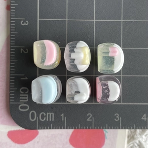 Macro detail of 1cm mini resin glitter juice bottles for DIY charms on a scale mat