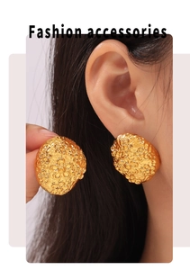 Detailed view of model wearing a large gold floral relief earring with matte texture