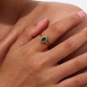Macro view of gold plated stainless steel ring with oval green stone and zircon halo