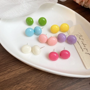 Close-up of vibrant candy-colored dome stud earrings displayed on a ceramic tray