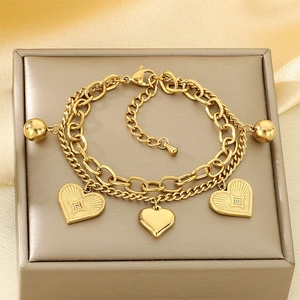 Detail of double-layer stainless steel gold bracelet with heart charms and ball beads