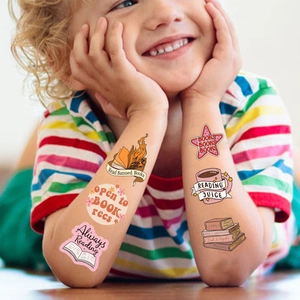 Child showing colorful reading themed temporary tattoos with book and coffee patterns