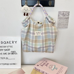 Detail of floral canvas tote bag featuring rainbow plaid pattern and purple star woven handles