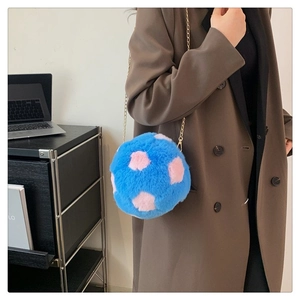 Close-up of fluffy blue plush shoulder bag with pink dots and gold chain strap on model