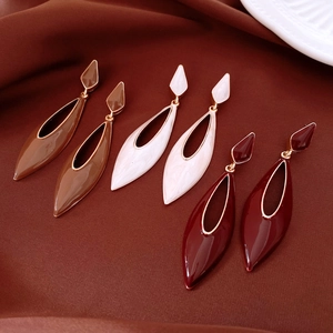 Détail de boucles d'oreilles en émail caramel, crème et bordeaux avec bordure dorée