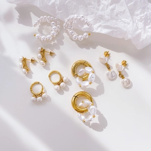 Flat lay of Hepburn style gold pearl earrings and fringe tassels on a white background
