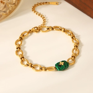 Detail of gold stainless steel bracelet with green malachite bead and clover pattern