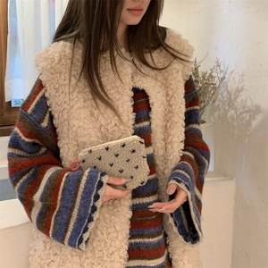 Detail of fleece pouch with blue flower embroidery held by model in winter outfit