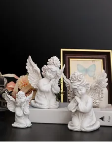 Detailed close-up of three white resin praying angel sculptures with intricate wing textures