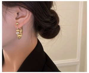 Detail of gold U-shaped earrings featuring textured metallic beads and crystal accents