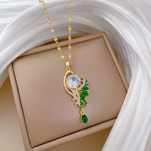 Detailed shot of peacock pendant with green gemstones and zircon on gold chain