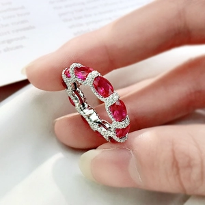 Macro shot of 925 silver eternity ring with oval rubies and white diamond accents