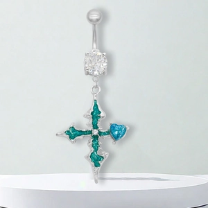 Détail macro d'un piercing de nombril croix gothique avec émail vert et cœur bleu