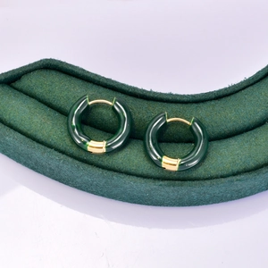 Détail de boucles d'oreilles créoles en résine vert foncé avec placage en or 18K