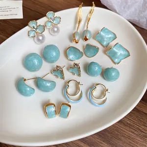 Elegant mint blue tulip floral earring set with gold accents and pearls on white tray