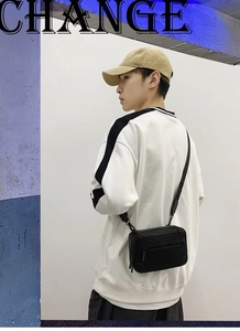 Detail of trendy black crossbody bag with double zippers and matte finish shown on model