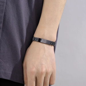 Detail of black stainless steel watchband style bracelet with flat engraving plate on wrist