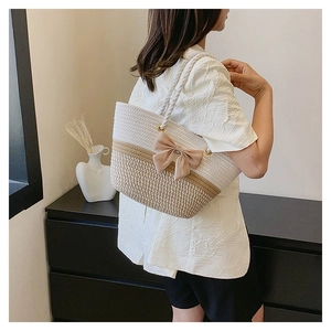 Detail of woven flower tote bag with decorative bow and rope handle on model